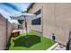 Backyard features artificial grass, a dog house, and a patio umbrella for shaded outdoor enjoyment at 8738 W Runion Dr, Peoria, AZ 85382
