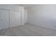 A minimalist bedroom featuring soft gray carpet, a closet with sliding doors, and crisp white walls at 1057 S 151St Ln, Goodyear, AZ 85338