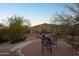 Scenic backyard featuring a brick patio, desert plants, mature trees, and views of the surrounding landscape at 11255 S San Adrian Ln, Goodyear, AZ 85338