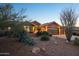 Beautiful desert home with manicured front yard landscaping and a spacious three car garage at dusk at 11255 S San Adrian Ln, Goodyear, AZ 85338