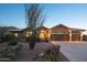 Exterior view of a home with desert landscaping, a tile roof, and a three-car garage at dusk at 11255 S San Adrian Ln, Goodyear, AZ 85338