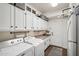 Functional laundry room with ample storage, white cabinets, sink, and washer and dryer hookups at 11255 S San Adrian Ln, Goodyear, AZ 85338