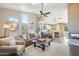 Comfortable living room with high ceilings, large windows, and open layout to the kitchen and fireplace at 11255 S San Adrian Ln, Goodyear, AZ 85338