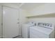 Bright laundry room with a full-size washer and dryer, plus a convenient shelf for storage and a door leading outside at 1335 E June St # 107, Mesa, AZ 85203