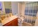 Accessible bathroom with a toilet with safety rails and a shower featuring a striped curtain for privacy at 1556 E Gabrilla Dr, Casa Grande, AZ 85122