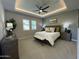 This is a spacious main bedroom with tray ceiling, a fan, a bench, and stylish decor at 15801 W Cielo Grande Ave, Surprise, AZ 85387