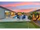 Stunning backyard with a pool, putting green, and vibrant sunset, ideal for relaxation at 16852 W Creedance Blvd, Surprise, AZ 85387