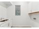 Functional laundry room featuring a sink, white cabinets, and a window with blinds at 16852 W Creedance Blvd, Surprise, AZ 85387