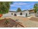 Spacious backyard showcasing fresh gravel, brick edging, and a white stucco home against a vibrant blue sky at 2122 W Virginia Ave, Phoenix, AZ 85009