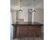 Spacious kitchen island features a dark countertop with wood cabinets and pull knobs, along with unique pendant lighting at 2233 E Behrend Dr # 203, Phoenix, AZ 85024
