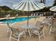 Community poolside seating area with multiple chairs and umbrella providing ample shade at 2233 E Behrend Dr # 203, Phoenix, AZ 85024