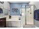Bathroom features a bathtub, glass-enclosed shower, and modern blue wall decor for a spa-like ambiance at 27007 N 20Th Ln, Phoenix, AZ 85085