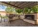 Outdoor kitchen boasts a built-in grill, bar seating, and a cozy fireplace under a pergola at 27007 N 20Th Ln, Phoenix, AZ 85085