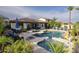 Backyard pool and spa with a rock waterfall, patio seating, outdoor dining area, and mature landscaping at 2991 E Fandango Dr, Gilbert, AZ 85298