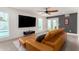 Bright living room with large tv, ceiling fan, and a sliding door leading to the green outdoors at 3038 E Avalon Dr, Phoenix, AZ 85016