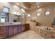 Spacious bathroom with double sinks, wood cabinets, tiled floors, and a separate soaking tub at 35195 N 98Th St # 85, Scottsdale, AZ 85262