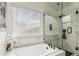 Luxurious bathroom featuring a soaking tub, glass-enclosed shower, white tile surround, and modern fixtures at 3703 S 73Rd Dr, Phoenix, AZ 85043