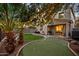 Charming backyard featuring a putting green, palm trees, string lights, and a covered patio with dining, ideal for entertaining at 3773 E Stampede Dr, Gilbert, AZ 85297