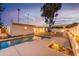 A refreshing pool with a modern deck and a covered lounge area enhances the backyard of this property at dusk at 4033 W Sharon Ave, Phoenix, AZ 85029