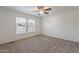 Calm bedroom showcasing neutral carpet, a ceiling fan, and a large window for abundant natural light and comfort at 46 S 96Th St, Mesa, AZ 85208