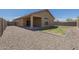 Backyard with gravel and grass, featuring a covered patio with a view of the property at 5096 S 245Th Dr, Buckeye, AZ 85326