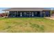 Expansive backyard with lush lawn, patio, and exterior view of the house with multiple access doors at 5321 N 196Th Ave, Litchfield Park, AZ 85340