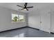 A simple bedroom with painted brick walls, a ceiling fan, and a large window with a palm tree view at 546 N 96Th Pl, Mesa, AZ 85207