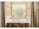 A relaxing tub is framed by a glass block window, inviting a spa-like atmosphere and natural light at 8603 E Aster Dr, Scottsdale, AZ 85260