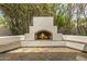 Outdoor fireplace on tiled patio with built in seating and lush green foliage in background at 8603 E Aster Dr, Scottsdale, AZ 85260