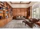Sophisticated library with a cozy seating area, wood paneling, and extensive built-in bookshelves at 8603 E Aster Dr, Scottsdale, AZ 85260