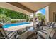 Relaxing covered patio featuring comfortable seating, pool, and lush backyard at 8603 E Aster Dr, Scottsdale, AZ 85260