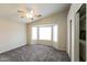 Light-filled bedroom with plush carpet, a ceiling fan, and a bay window overlooking the front yard at 8832 W Manzanita Dr, Peoria, AZ 85345