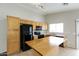 Bright kitchen with black appliances, light wood cabinets, tile flooring, and a breakfast bar at 8832 W Manzanita Dr, Peoria, AZ 85345