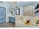 Light and airy bathroom with a large soaking tub, double sink vanity and decorative glass block window at 10226 W Country Club Trl, Peoria, AZ 85383