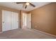 Bedroom with carpeted floor, ceiling fan, tan walls, white double closet doors, and standard doorway at 1086 S Nancy Ln, Gilbert, AZ 85296