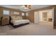 Comfortable bedroom boasts a ceiling fan, large bed, and windows with stylish shutters, leading to a hallway at 1086 S Nancy Ln, Gilbert, AZ 85296