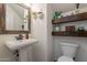 Chic powder room featuring a pedestal sink, decorative mirror, and floating wooden shelves at 1086 S Nancy Ln, Gilbert, AZ 85296