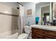 Well-lit bathroom featuring a shower-tub combo, a vanity with a wooden base, and a decorative wall sign at 12834 W Forest Pleasant Pl, Peoria, AZ 85383