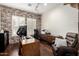 Inviting home office space featuring brick accent wall, wood floors, desk, workstation, and comfortable leather chair at 12834 W Forest Pleasant Pl, Peoria, AZ 85383