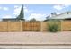 A tan brick fence with a wooden gate is set in a gravel yard outside the home at 1408 N 62Nd Pl, Mesa, AZ 85205