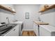 Well-lit laundry room with modern appliances, rustic shelves, and a stylish utility sink at 1408 N 62Nd Pl, Mesa, AZ 85205