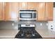 Close-up shot of the kitchen with stainless steel appliances and hardwood cabinets at 16039 W Pima St, Goodyear, AZ 85338