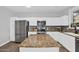 Updated kitchen features stainless appliances, a stone backsplash and a large center island with granite countertop at 16139 N 171St Ln, Surprise, AZ 85388