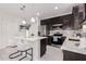 Well-lit kitchen with stainless steel appliances, dark cabinetry, quartz countertops, and bar seating at 18247 W Soft Wind Dr, Surprise, AZ 85387