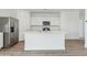 Kitchen island with sink, white cabinetry, stainless steel refrigerator, and wood-look floors at 18795 E Bruno Dr, Gold Canyon, AZ 85118