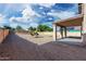 Expansive backyard with gravel, a brick fence, and trees, shaded by a covered patio with a balcony at 22074 W Papago St, Buckeye, AZ 85326