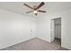 Bedroom features neutral carpet, a ceiling fan, closet, and a door at 22074 W Papago St, Buckeye, AZ 85326