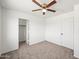 A well-lit bedroom featuring neutral carpet, a ceiling fan, closet, and a door at 22074 W Papago St, Buckeye, AZ 85326