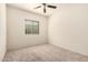 This bedroom features neutral carpet, a ceiling fan, window and light-colored walls at 24627 W Ripple Rd, Buckeye, AZ 85326