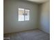 Bedroom features neutral carpet and a window with a view of the block wall at 24627 W Ripple Rd, Buckeye, AZ 85326